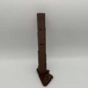 Può includere: Un modello architettonico verticale marrone di un grattacielo, caratterizzato da un design a gradini su più livelli con una struttura stretta e allungata. La base è più ampia e angolare, a sostegno della torre sottile e strutturata.