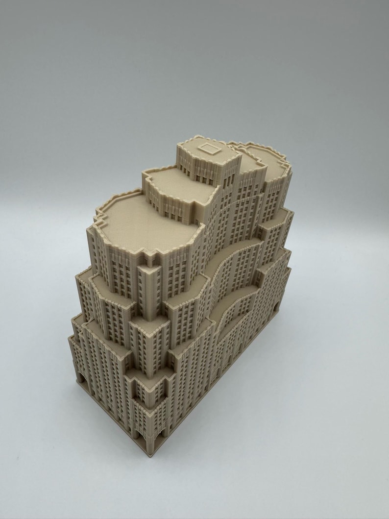 May include: A beige architectural model of a multi-storey building with a stepped design. The model features numerous windows and detailed facade elements, showcasing a classic skyscraper aesthetic. The building's structure is complex, with varying heights and setbacks.