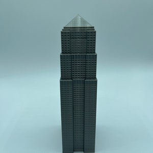Peut inclure: Mod&egrave;le 3D imprim&eacute; en gris d'un gratte-ciel avec un toit pointu et de nombreuses fen&ecirc;tres.