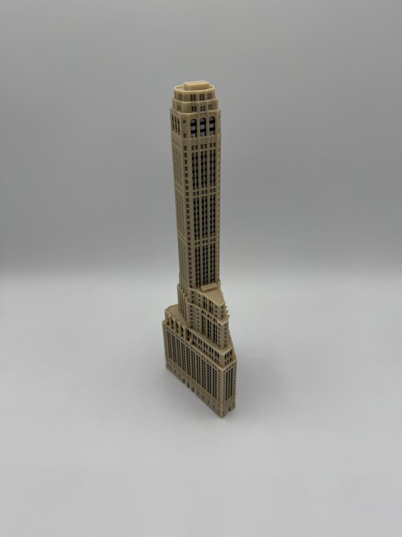 Op de afbeelding: Een beige 3D-geprint model van een hoog wolkenkrabbergebouw met een gedetailleerde gevel.