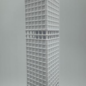 May include: A white, 3D-printed model of a skyscraper. The rectangular building features a grid of windows and open sections. The model is a detailed architectural representation, likely made using a 3D printer.
