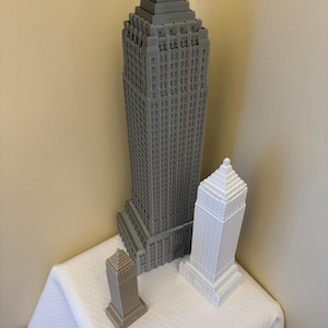 Puede incluir: Tres modelos de rascacielos impresos en 3D en diferentes tonos de gris. El edificio m&aacute;s alto es gris oscuro, el edificio del medio es gris claro y el edificio m&aacute;s peque&ntilde;o es gris marr&oacute;n.