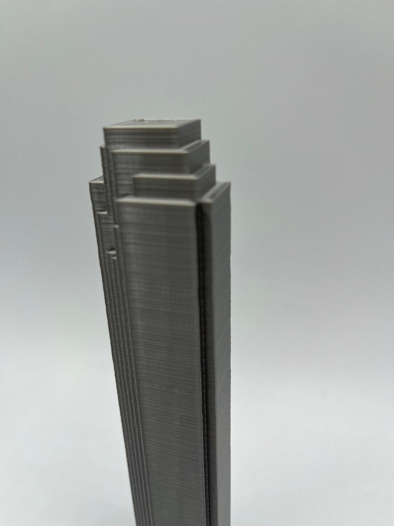 May include: A gray 3D printed model of a skyscraper with a layered design.