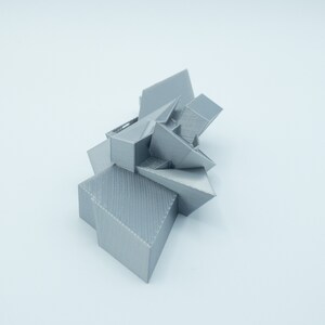May include: A silver 3D printed geometric sculpture with sharp angles and a textured surface.