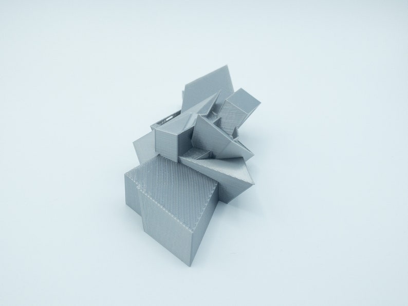 May include: A silver 3D printed geometric sculpture with sharp angles and a textured surface.