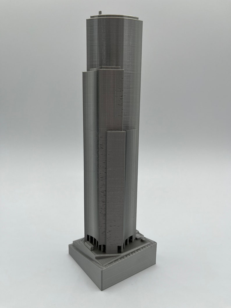 May include: A gray 3D printed model of a skyscraper with a square base.