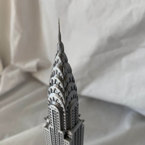 Puede incluir: Un modelo plateado del edificio Chrysler, un famoso rascacielos de la ciudad de Nueva York. El modelo es detallado e incluye la ic&oacute;nica aguja del edificio.