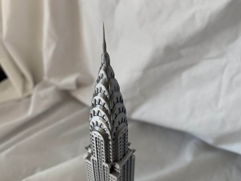 Puede incluir: Un modelo plateado del edificio Chrysler, un famoso rascacielos de la ciudad de Nueva York. El modelo es detallado e incluye la ic&oacute;nica aguja del edificio.
