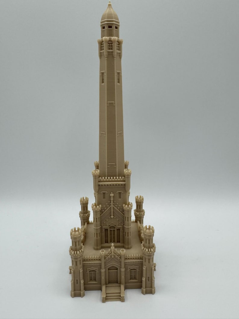 May include: A beige architectural model of a tall tower with intricate details, including turrets, windows, and a domed top. The model is a detailed replica of a historic building, showcasing its architectural features.
