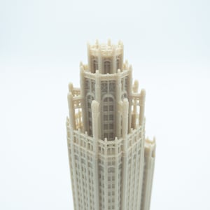 May include: A detailed 3D printed model of a tall building with a decorative top and many windows.