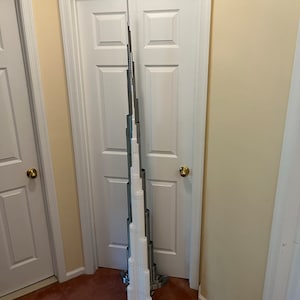 May include: A white model of the Burj Khalifa, a skyscraper in Dubai, standing in a hallway with two white doors.