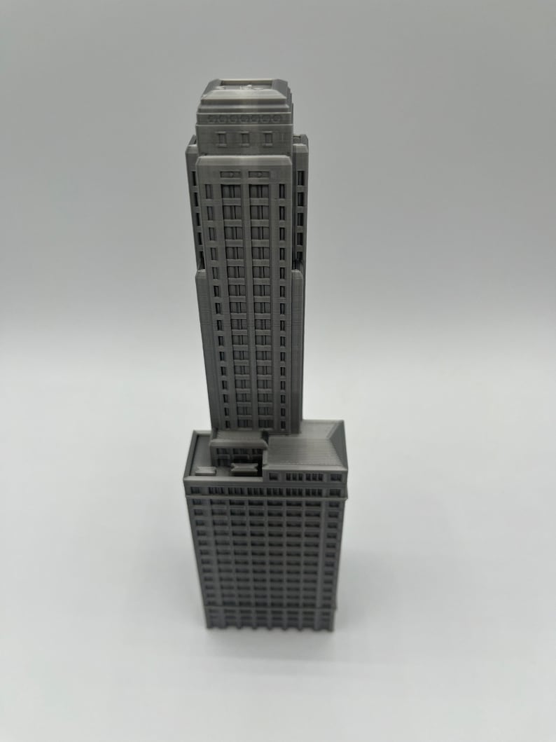 May include: A gray 3D printed model of a tall skyscraper building with a flat roof and many windows.