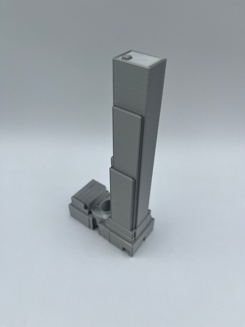 May include: A gray 3D printed model of a skyscraper with a flat roof and multiple windows.