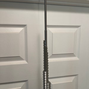 May include: A silver metal model of a skyscraper, resembling the Burj Khalifa, with a detailed design of stacked rings.