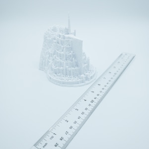 May include: A white 3D printed model of a castle, approximately 6 inches tall, with a ruler for scale.