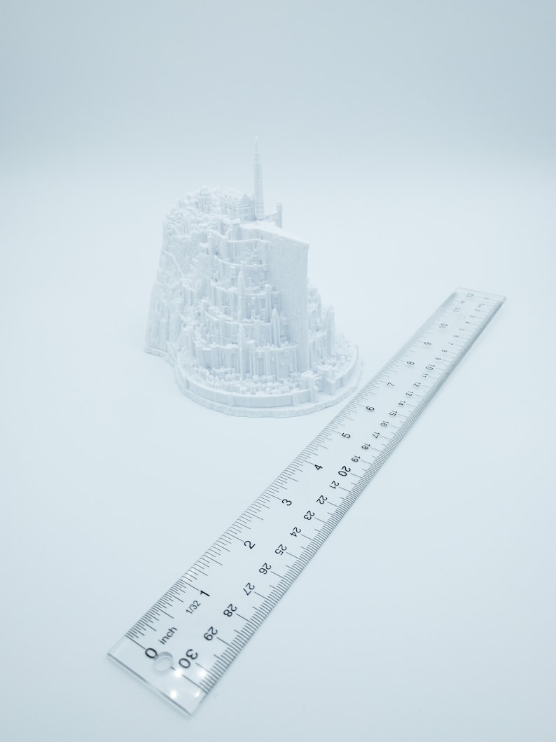 May include: A white 3D printed model of a castle, approximately 6 inches tall, with a ruler for scale.