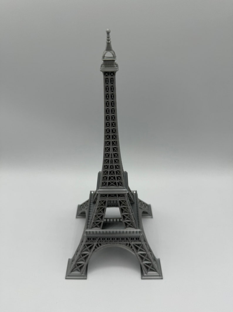 May include: A gray metal Eiffel Tower model. The model is detailed with intricate latticework and a pointed spire.