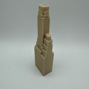 May include: A beige 3D printed model of a skyscraper with a flat roof and many windows.