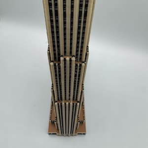 Puede incluir: Una maqueta en miniatura de un rascacielos. El modelo est&aacute; construido con materiales beige claro y marr&oacute;n oscuro, con un dise&ntilde;o detallado que imita la apariencia de un edificio moderno de gran altura. La estructura tiene una base rectangular.