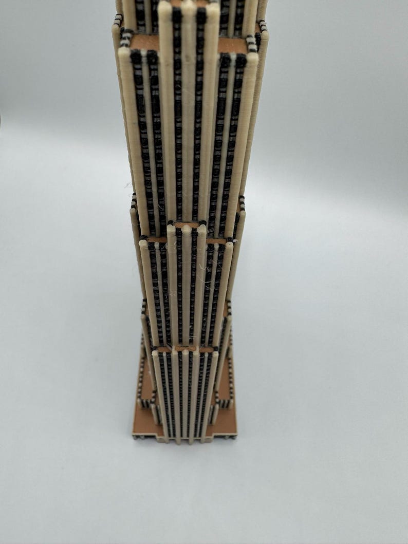 Puede incluir: Una maqueta en miniatura de un rascacielos. El modelo est&aacute; construido con materiales beige claro y marr&oacute;n oscuro, con un dise&ntilde;o detallado que imita la apariencia de un edificio moderno de gran altura. La estructura tiene una base rectangular.