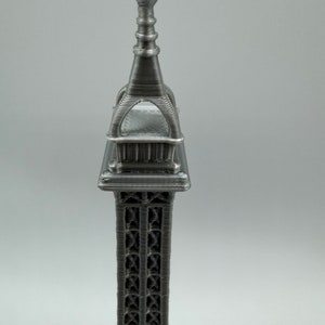 May include: A silver metal Eiffel Tower replica with intricate details. The tower is a popular souvenir and decorative item.