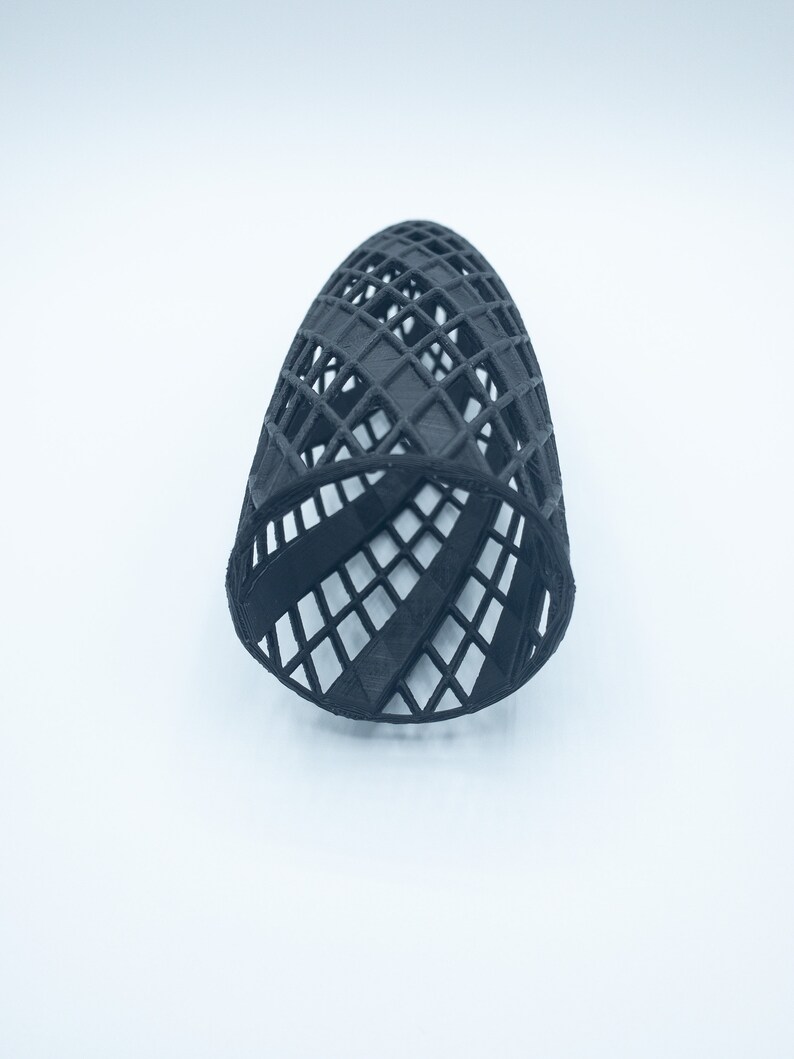 May include: A black, 3D printed, geometric, cylindrical shaped object with a lattice design.