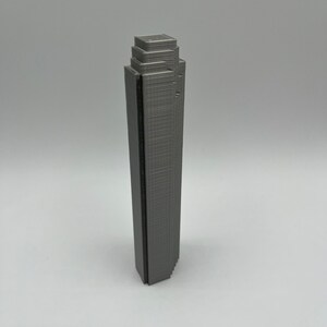 May include: A gray 3D printed model of a skyscraper.
