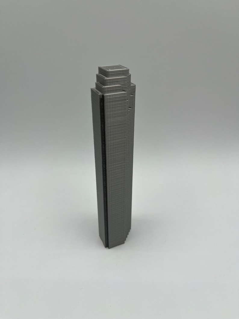 May include: A gray 3D printed model of a skyscraper.