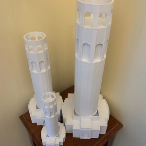 Może przedstawiać: Trzy białe modele Golden Gate Bridge, ikonicznego pomnika San Francisco, wydrukowane w 3D. Modele są w r&oacute;żnych rozmiarach, a największy ma około 30 cm wysokości.