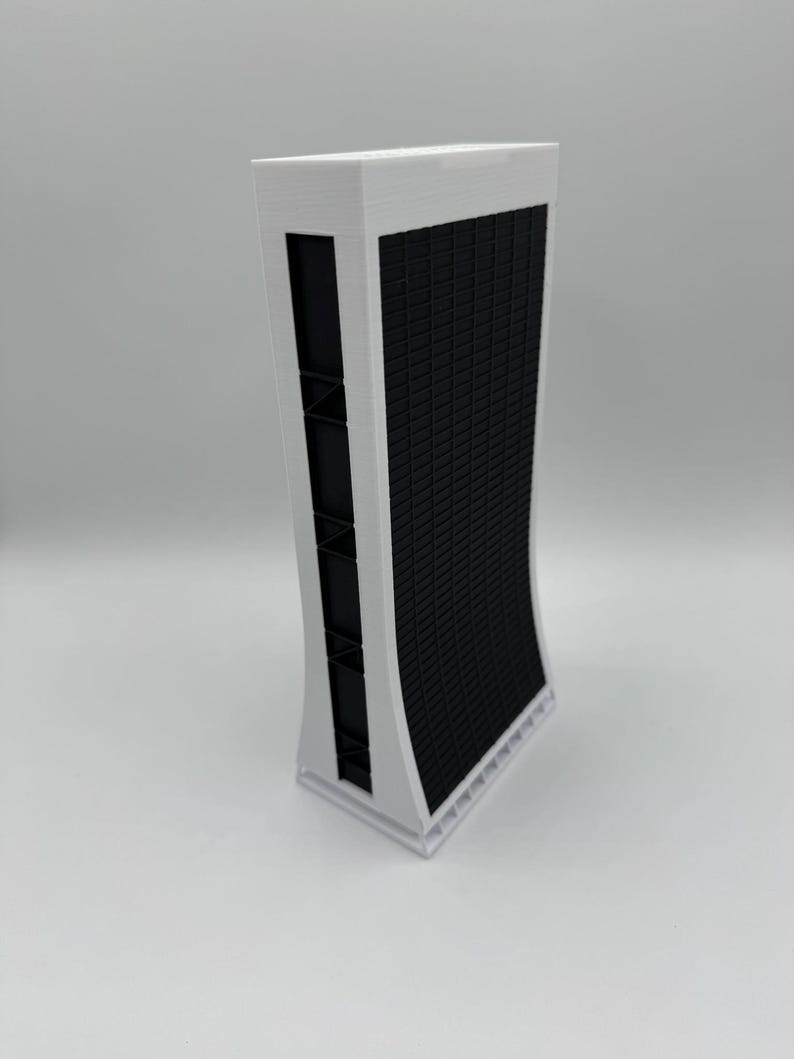 May include: A white 3D printed model of a tall, modern building with a black grid pattern on the front.