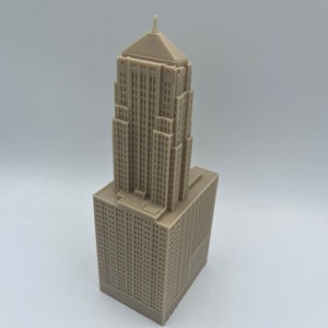 May include: A beige 3D printed model of a tall building with a pointed roof.