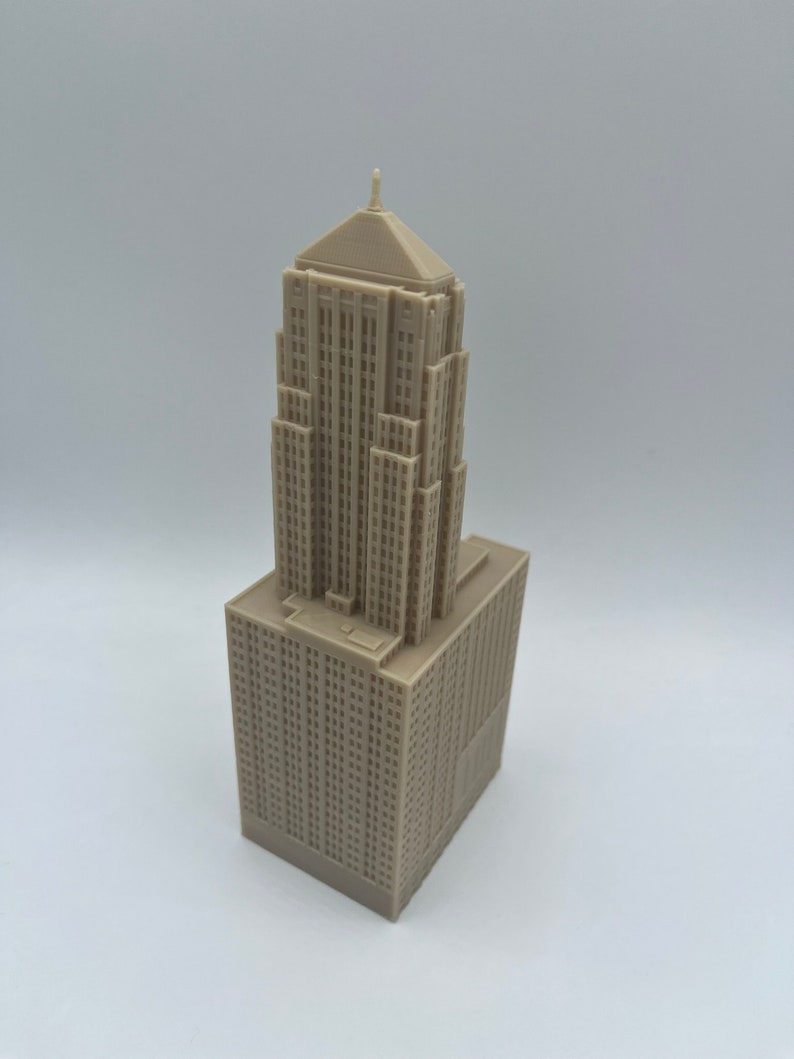 May include: A beige 3D printed model of a tall building with a pointed roof.