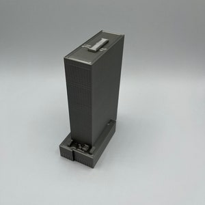 May include: A gray 3D printed model of a skyscraper building.