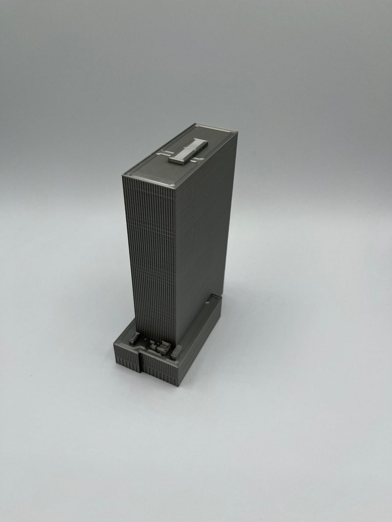 May include: A gray 3D printed model of a skyscraper building.