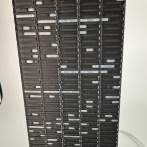 Peut inclure: Gros plan d'un objet rectangulaire noir avec un motif r&eacute;p&eacute;titif de lignes horizontales et de petites ouvertures rectangulaires. L'objet semble &ecirc;tre fait d'un mat&eacute;riau rigide, peut-&ecirc;tre du plastique ou du m&eacute;tal. Les ouvertures sont remplies d'un mat&eacute;riau plus clair.