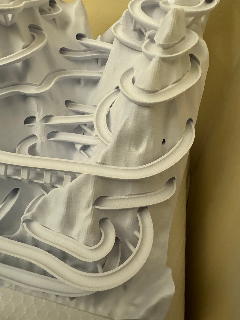 Puede incluir: Modelo 3D impreso en blanco de una monta&ntilde;a con una compleja red de pistas y t&uacute;neles sinuosos.