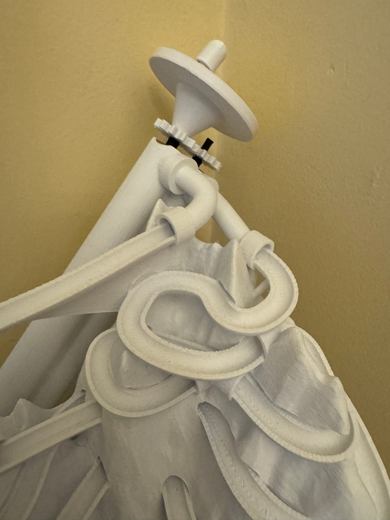 Puede incluir: Escultura blanca impresa en 3D de una persona con un sombrero grande y un complejo sistema de pistas sinuoso. El sistema de pistas est&aacute; hecho de pl&aacute;stico blanco y parece ser una pista de canicas.