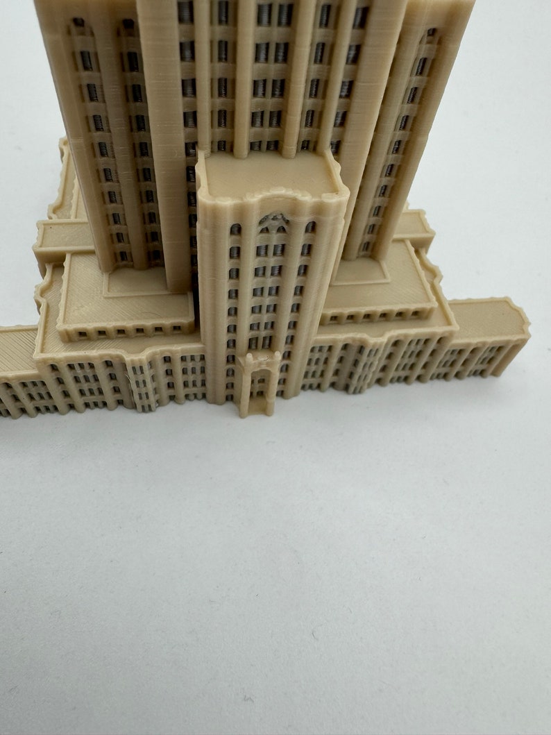 May include: A beige 3D printed model of a skyscraper with a detailed facade and multiple windows.