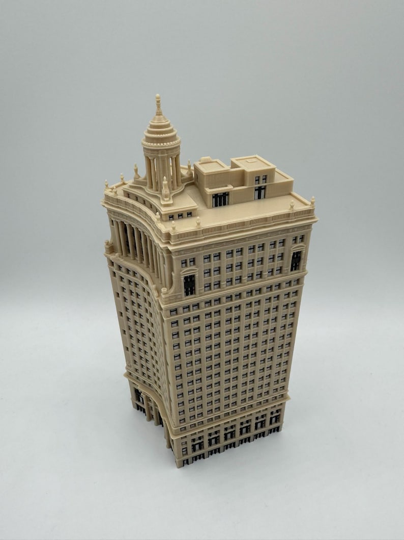 Op de afbeelding: Een beige miniatuurmodel van een hoog, versierd gebouw met een koepelvormig dak. Het gebouw heeft veel ramen en een gebogen gevel.