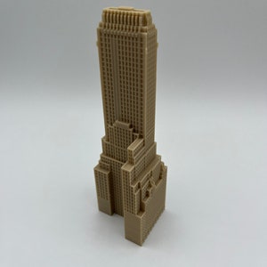 May include: A beige 3D printed model of a skyscraper building.