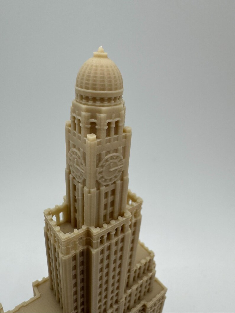 May include: A beige 3D printed model of a tall building with a domed roof and a clock face. The building has many windows and intricate details.