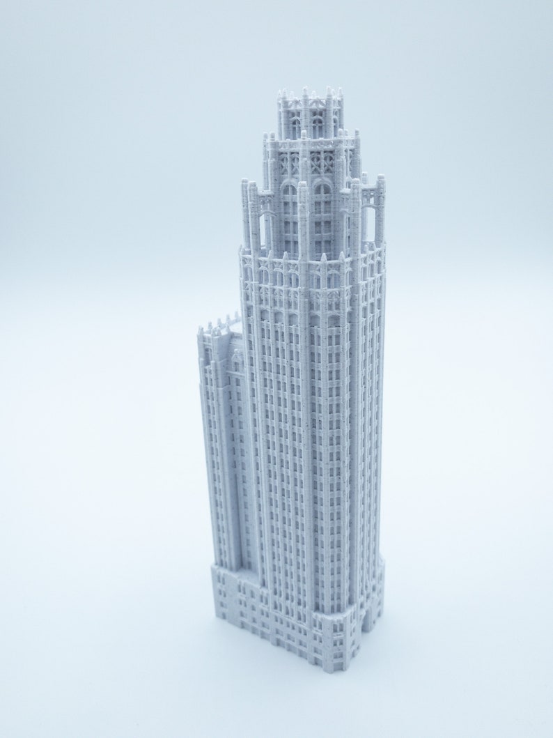 May include: A white 3D printed model of a tall, ornate building with a pointed roof and many windows.