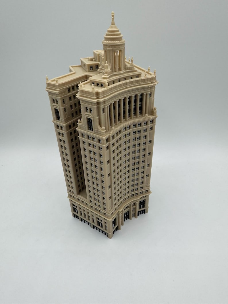 Op de afbeelding: Een gedetailleerd 3D-geprint model van een hoog, beige gebouw met een gebogen gevel en een koepelvormig dak.