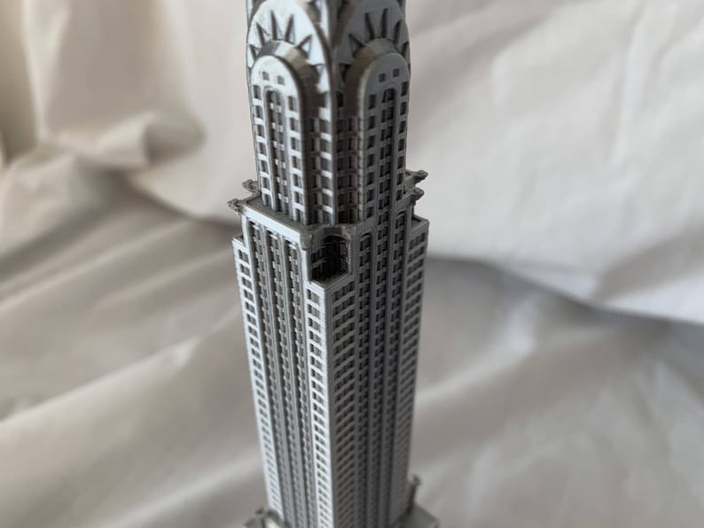 Puede incluir: Una maqueta detallada del Chrysler Building, un famoso rascacielos Art Deco en la ciudad de Nueva York. La maqueta est&aacute; hecha de un material de color plateado y presenta detalles intrincados, incluida la distintiva aguja del edificio.