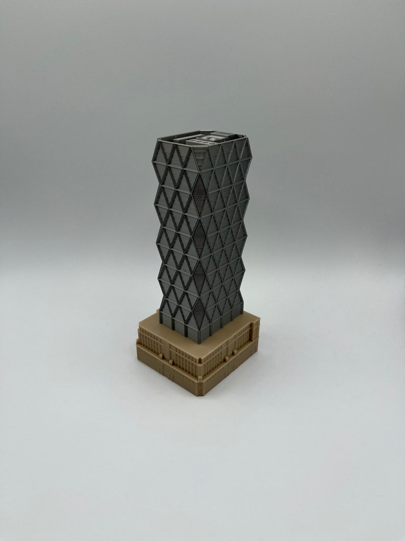 May include: A grey and black model of a skyscraper with a geometric design. The building has a brown base.