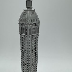 May include: A 3D printed model of a tall, gray building with a detailed, ornate roof and many windows.