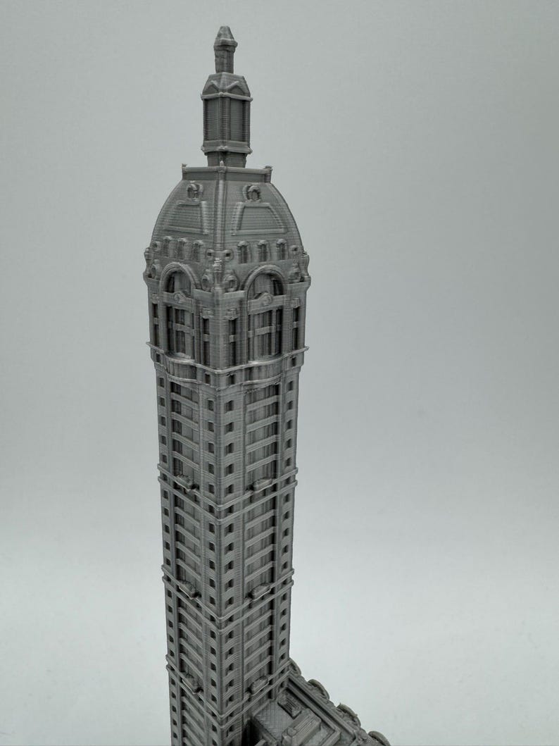 May include: A 3D printed model of a tall, gray building with a detailed, ornate roof and many windows.