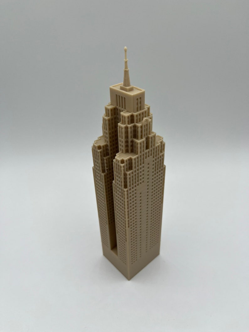 May include: A beige 3D printed model of a skyscraper with a pointed roof and many windows.