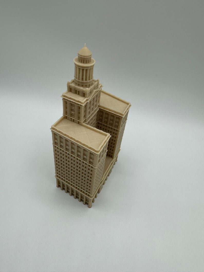 May include: A beige 3D printed model of a tall building with a tower on top. The building has many windows and is detailed with intricate architectural features.