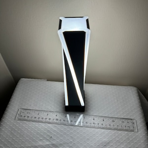 May include: A black and white geometric lamp with a white light source. The lamp is about 7 inches tall.
